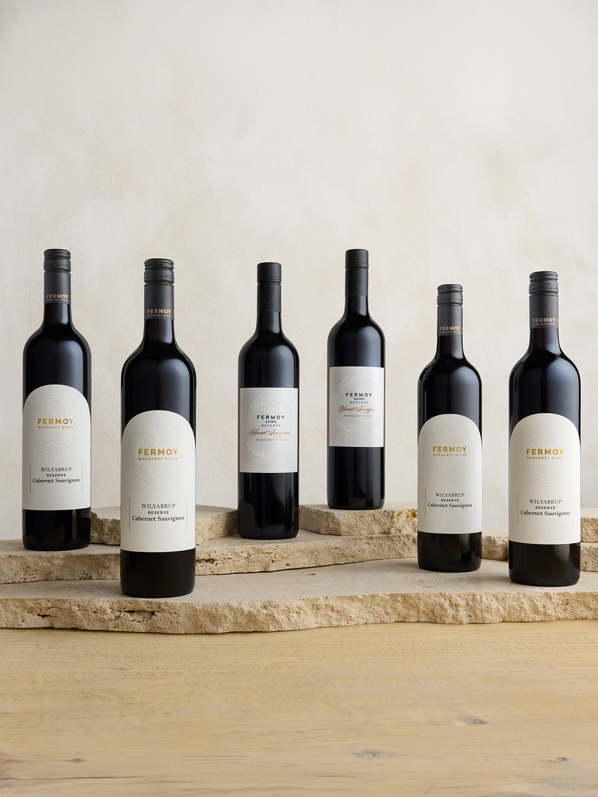 Six bottles of Fermoy Wilyabrup Reserve Cabernet Sauvignon arranged on a wooden surface with a neutral background