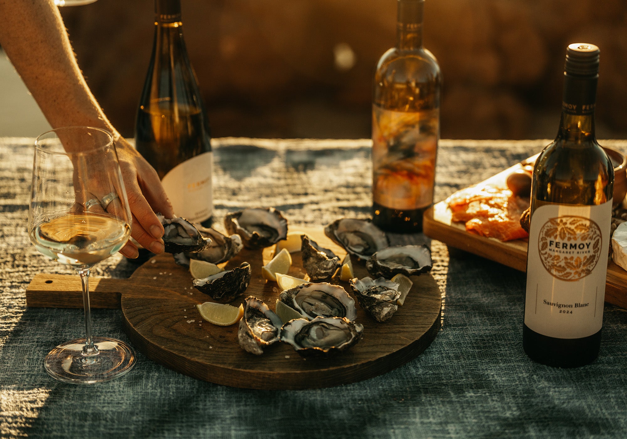Elliott’s at Fermoy winery- oysters on a wooden plate with a wine bottle and glass on a table.